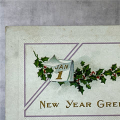 Embossed vintage New Year postcard with holly leaves and berries framing a gold “JAN 1” calendar; “New Year Greetings” printed in gold below. Made by Stechler Litho Co., postmarked December 1920.