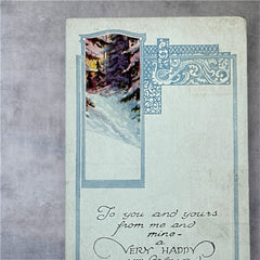 Printed vintage New Year postcard with a snowy forest illustration and ornate blue scrollwork; greeting reads “To you and yours from me and mine — a VERY HAPPY NEW YEAR.” Postmarked December 1923.