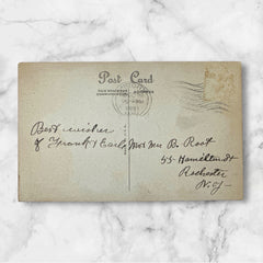 Printed vintage New Year postcard with a snowy forest illustration and ornate blue scrollwork; greeting reads “To you and yours from me and mine — a VERY HAPPY NEW YEAR.” Postmarked December 1923.