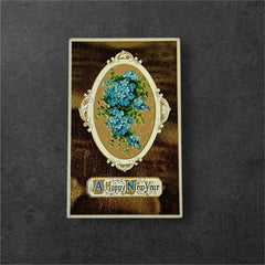 Antique 1910s New Year postcard featuring embossed blue forget-me-not flowers in a gold-gilded oval frame, set against a textured brown background resembling crocodile skin; elegant and well-preserved with handwritten 1913 message on reverse.