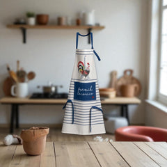 Eco-friendly French kitchen apron featuring a stylized rooster and Eiffel Tower illustration with the phrase 'French Cocorico' on a white background with blue stripes and matching blue ties.