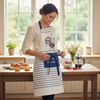 Eco-friendly French kitchen apron featuring a stylized rooster and Eiffel Tower illustration with the phrase 'French Cocorico' on a white background with blue stripes and matching blue ties.