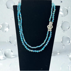 Vintage double‑strand aqua blue AB crystal necklace with faceted beads and a silver‑tone pavé rhinestone brooch clasp, shown from multiple angles to highlight bead size, sparkle, and clasp detailing.