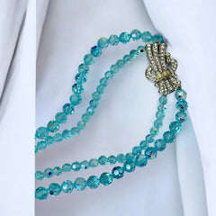 Vintage double‑strand aqua blue AB crystal necklace with faceted beads and a silver‑tone pavé rhinestone brooch clasp, shown from multiple angles to highlight bead size, sparkle, and clasp detailing.