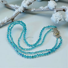 Vintage double‑strand aqua blue AB crystal necklace with faceted beads and a silver‑tone pavé rhinestone brooch clasp, shown from multiple angles to highlight bead size, sparkle, and clasp detailing.