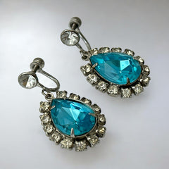 A pair of vintage 1950s–60s silver‑tone screw‑back earrings with aqua pear rhinestones and clear accent stones, shown from different angles to highlight their shape and condition.