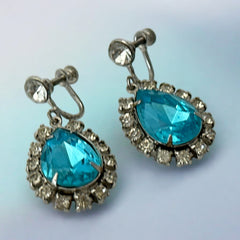 A pair of vintage 1950s–60s silver‑tone screw‑back earrings with aqua pear rhinestones and clear accent stones, shown from different angles to highlight their shape and condition.