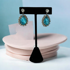 A pair of vintage 1950s–60s silver‑tone screw‑back earrings with aqua pear rhinestones and clear accent stones, shown from different angles to highlight their shape and condition.
