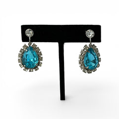 A pair of vintage 1950s–60s silver‑tone screw‑back earrings with aqua pear rhinestones and clear accent stones, shown from different angles to highlight their shape and condition.