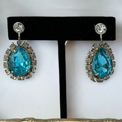 A pair of vintage 1950s–60s silver‑tone screw‑back earrings with aqua pear rhinestones and clear accent stones, shown from different angles to highlight their shape and condition.