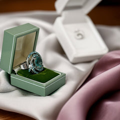 Adjustable silver-tone cocktail ring with a large round aqua rhinestone cabochon and open swirl design set with smaller teal rhinestones; vintage-inspired statement jewelry in very good condition.