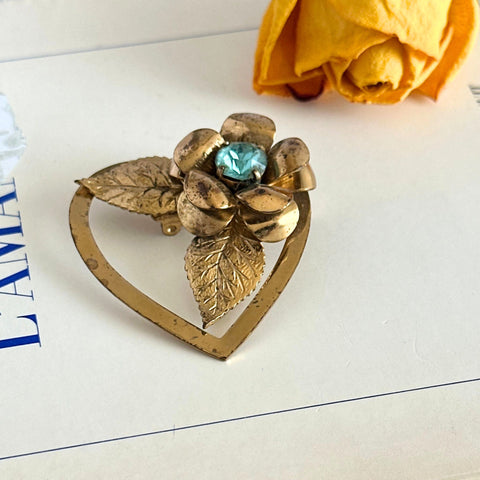 Vintage gold‑tone Coro heart brooch with raised floral motif and aqua rhinestone center.