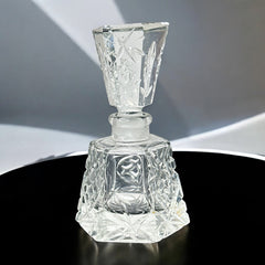Vintage Czech hand-cut glass perfume bottle with faceted hexagon base and original stopper, shown in varied lighting to highlight its Art Deco silhouette and reflective clarity.
