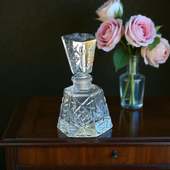 Vintage Czech hand-cut glass perfume bottle with faceted hexagon base and original stopper, shown in varied lighting to highlight its Art Deco silhouette and reflective clarity.