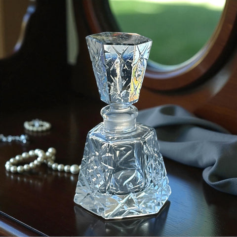 Vintage Czech hand-cut glass perfume bottle with faceted hexagon base and original stopper, shown in varied lighting to highlight its Art Deco silhouette and reflective clarity.