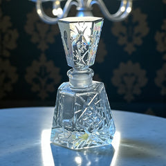 Vintage Czech hand-cut glass perfume bottle with faceted hexagon base and original stopper, shown in varied lighting to highlight its Art Deco silhouette and reflective clarity.