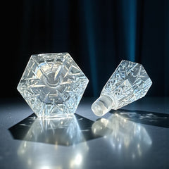 Vintage Czech hand-cut glass perfume bottle with faceted hexagon base and original stopper, shown in varied lighting to highlight its Art Deco silhouette and reflective clarity.