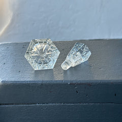 Vintage Czech hand-cut glass perfume bottle with faceted hexagon base and original stopper, shown in varied lighting to highlight its Art Deco silhouette and reflective clarity.