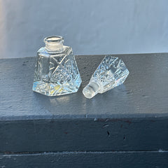 Vintage Czech hand-cut glass perfume bottle with faceted hexagon base and original stopper, shown in varied lighting to highlight its Art Deco silhouette and reflective clarity.