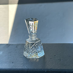 Vintage Czech hand-cut glass perfume bottle with faceted hexagon base and original stopper, shown in varied lighting to highlight its Art Deco silhouette and reflective clarity.