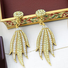 Vintage gold-tone clip-on earrings with jonquil and clear rhinestones in a feather-like Art Deco revival design; long dangle silhouette, 1970s style.