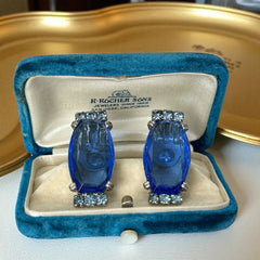 Vintage clip-on earrings featuring large cobalt blue oval rhinestones with light blue chaton accents in silver-tone Art Deco-style settings, mid-century design.