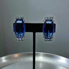 Vintage clip-on earrings featuring large cobalt blue oval rhinestones with light blue chaton accents in silver-tone Art Deco-style settings, mid-century design.