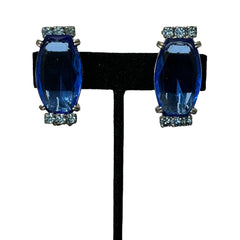 Vintage clip-on earrings featuring large cobalt blue oval rhinestones with light blue chaton accents in silver-tone Art Deco-style settings, mid-century design.