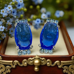 Vintage clip-on earrings featuring large cobalt blue oval rhinestones with light blue chaton accents in silver-tone Art Deco-style settings, mid-century design.