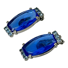 Vintage clip-on earrings featuring large cobalt blue oval rhinestones with light blue chaton accents in silver-tone Art Deco-style settings, mid-century design.