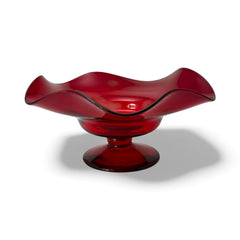 Vintage ruby red hand-blown glass bowl with a freeform wavy rim and clear pedestal base, photographed from above to highlight its organic curves and glossy surface. Midcentury compote style, ideal for decorative or serving use.