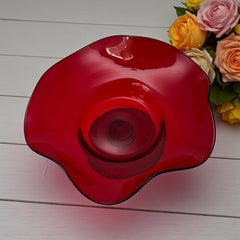 Vintage ruby red hand-blown glass bowl with a freeform wavy rim and clear pedestal base, photographed from above to highlight its organic curves and glossy surface. Midcentury compote style, ideal for decorative or serving use.