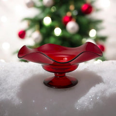 Vintage ruby red hand-blown glass bowl with a freeform wavy rim and clear pedestal base, photographed from above to highlight its organic curves and glossy surface. Midcentury compote style, ideal for decorative or serving use.