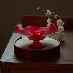 Vintage ruby red hand-blown glass bowl with a freeform wavy rim and clear pedestal base, photographed from above to highlight its organic curves and glossy surface. Midcentury compote style, ideal for decorative or serving use.