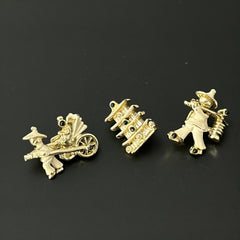Set of three vintage Asian-themed scatter brooches in white enamel and gold tone, featuring a rickshaw scene, a pagoda, and a man carrying food boxes on a shoulder cane, displayed on a black background.
