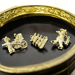 Set of three vintage Asian-themed scatter brooches in white enamel and gold tone, featuring a rickshaw scene, a pagoda, and a man carrying food boxes on a shoulder cane, displayed on a black background.