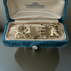 Set of three vintage Asian-themed scatter brooches in white enamel and gold tone, featuring a rickshaw scene, a pagoda, and a man carrying food boxes on a shoulder cane, displayed on a black background.