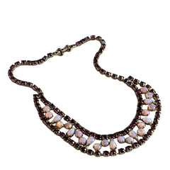 A vintage Astra necklace featuring glowing faux opal cabochons and deep amethyst stones in a double‑row midcentury design, shown on a neutral background to highlight its color and detail.