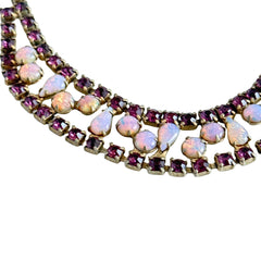 A vintage Astra necklace featuring glowing faux opal cabochons and deep amethyst stones in a double‑row midcentury design, shown on a neutral background to highlight its color and detail.