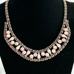 A vintage Astra necklace featuring glowing faux opal cabochons and deep amethyst stones in a double‑row midcentury design, shown on a neutral background to highlight its color and detail.