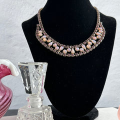 A vintage Astra necklace featuring glowing faux opal cabochons and deep amethyst stones in a double‑row midcentury design, shown on a neutral background to highlight its color and detail.
