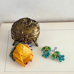 Vintage Austrian blue and green granulated enamel floral clip‑on earrings with rhinestone accents, shown from multiple angles to display their mid‑century design.