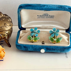 Vintage Austrian blue and green granulated enamel floral clip‑on earrings with rhinestone accents, shown from multiple angles to display their mid‑century design.