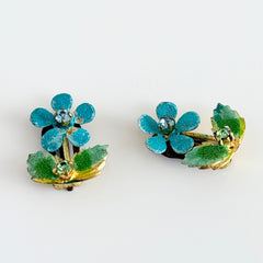 Vintage Austrian blue and green granulated enamel floral clip‑on earrings with rhinestone accents, shown from multiple angles to display their mid‑century design.