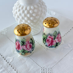 Vintage Austrian porcelain salt and pepper shakers hand‑painted with pink roses and gold tops, shown from multiple angles on a white background.