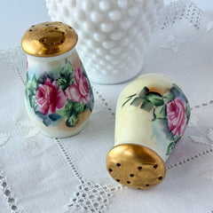 Vintage Austrian porcelain salt and pepper shakers hand‑painted with pink roses and gold tops, shown from multiple angles on a white background.