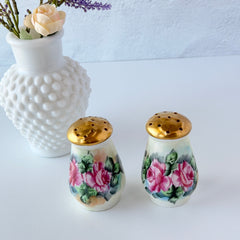 Vintage Austrian porcelain salt and pepper shakers hand‑painted with pink roses and gold tops, shown from multiple angles on a white background.