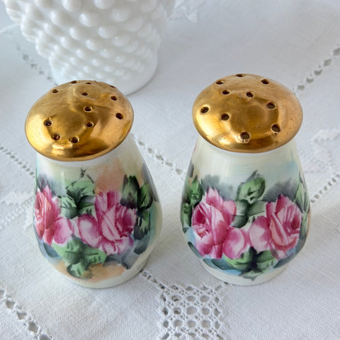 Vintage Austrian porcelain salt and pepper shakers hand‑painted with pink roses and gold tops, shown from multiple angles on a white background.