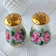 Vintage Austrian porcelain salt and pepper shakers hand‑painted with pink roses and gold tops, shown from multiple angles on a white background.