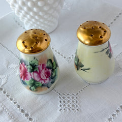 Vintage Austrian porcelain salt and pepper shakers hand‑painted with pink roses and gold tops, shown from multiple angles on a white background.